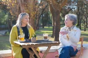 Two elderly women sat at a small table outside